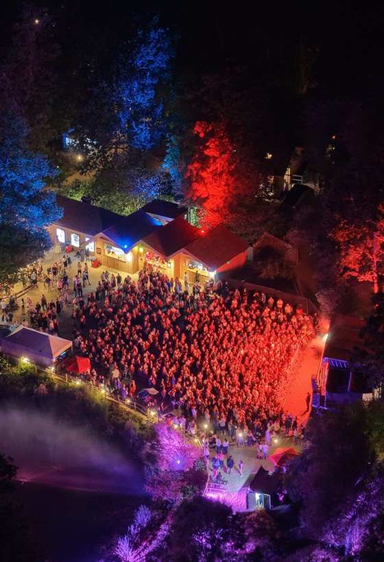 A festival arena lit at night, shot from the air